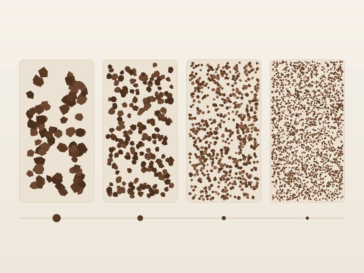 Four trays of ground coffee side by side, the fragments getting steadily smaller from left to right, ending in a near-powder.