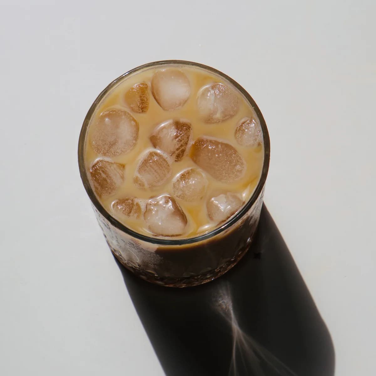 A glass of cold brew coffee with milk and ice cubes, seen from above.